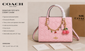 Pink Coach tote bag with cherry charm on a beige background