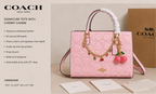 Pink Coach tote bag with cherry charm on a beige background